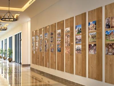 Heller Hotelflur mit Holzwänden und dekorativen Bildern, großen Fenstern und Kronleuchtern