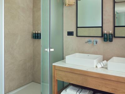 Moderner Badbereich mit begehbarer Dusche, Glaswand, rechteckigem Waschbecken und Holzregal mit Handtüchern.