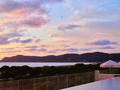 Sonnenuntergang über Berg und Meer, mit rosa Wolken und Terrasse im Vordergrund.