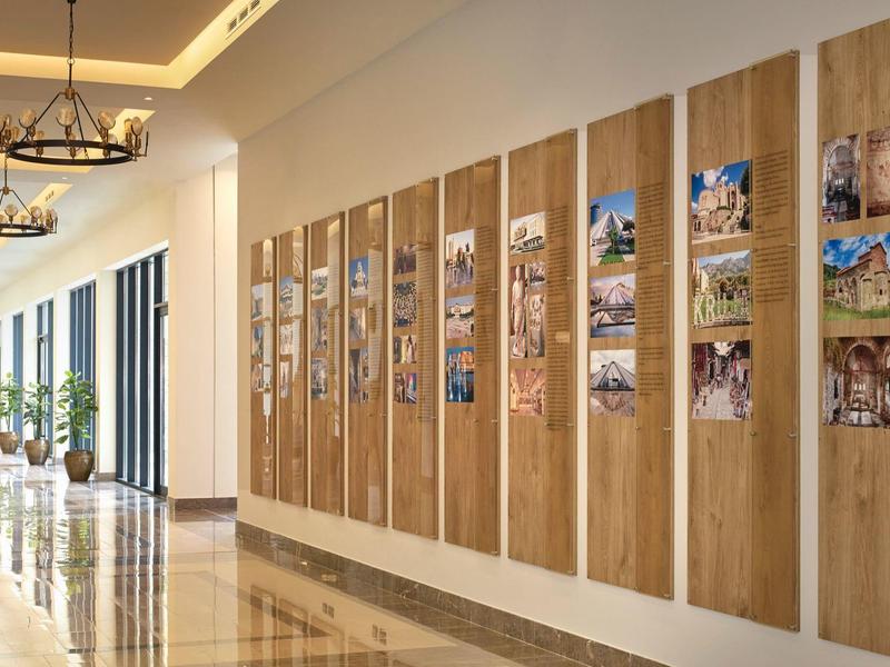 Langer Flur mit Holztafeln, auf denen Fotos angeordnet sind, und modernen Kronleuchtern.