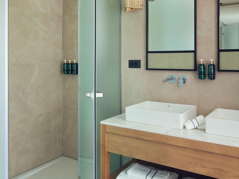 Moderner Badbereich mit begehbarer Dusche, Glaswand, rechteckigem Waschbecken und Holzregal mit Handtüchern.