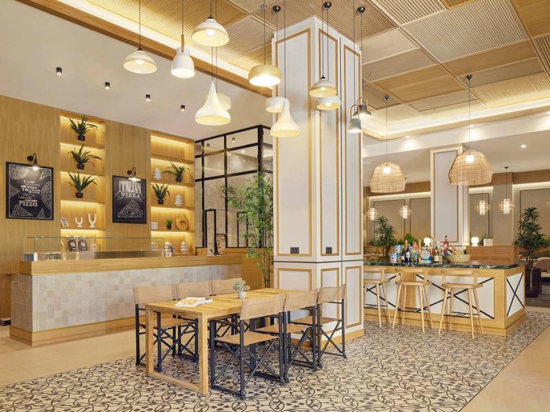 Modernes Café mit Holz- und Marmormöbeln, warmem Licht, Pflanzen und dekorativen Pendelleuchten.