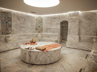 Luxurious marble steam room with rounded seating and decorative wall tiles.