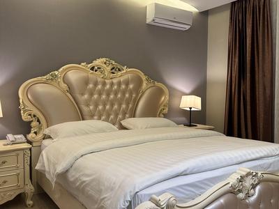 Elegantes Schlafzimmer mit hochwertigem, verziertem Doppelbett, Nachttischen und sanfter Beleuchtung.
