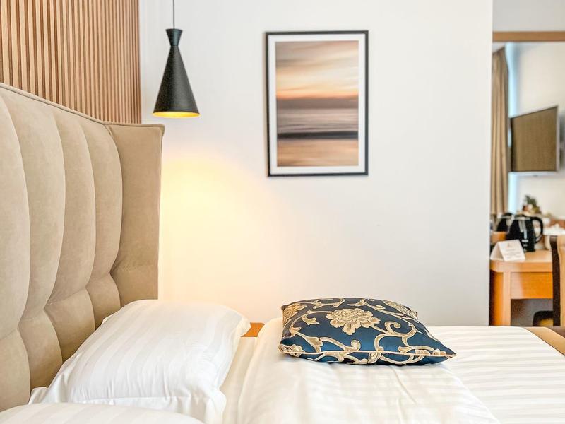 Modern hotel room with bed, patterned pillows, and framed picture on the wall.