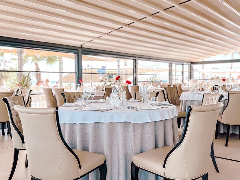 Elegant restaurant with round table, beige chairs, and large windows.