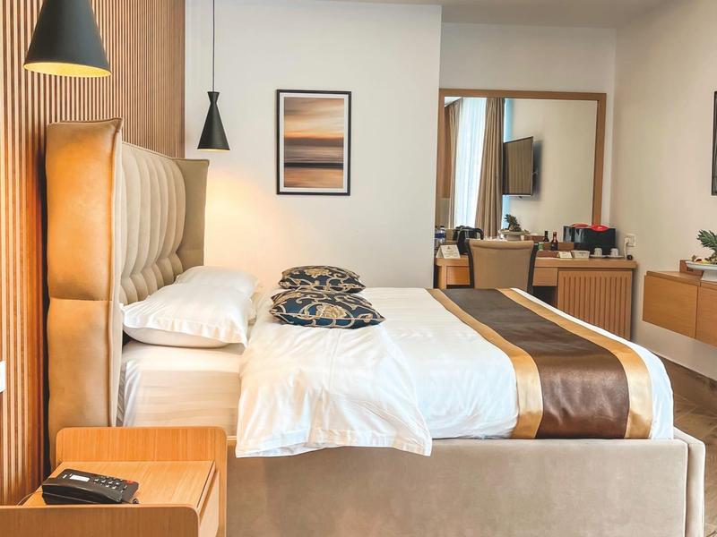 Modern hotel room with large bed, wooden accents, and soft lighting.