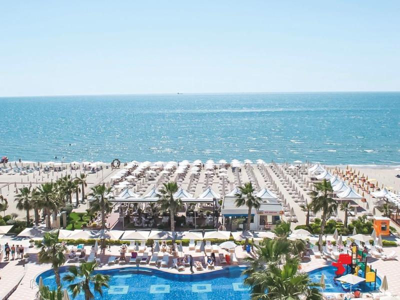 Large pool with sun loungers and a view of the beach and sea on a sunny day