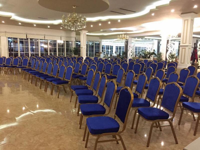 An event room with multiple rows of blue chairs on a shiny marble floor.