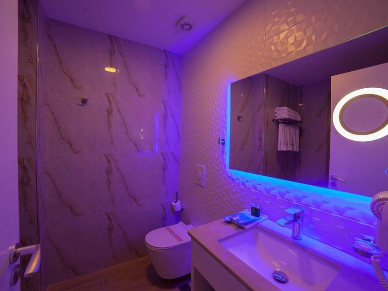 Modern bathroom with illuminated mirror and purple LED lighting