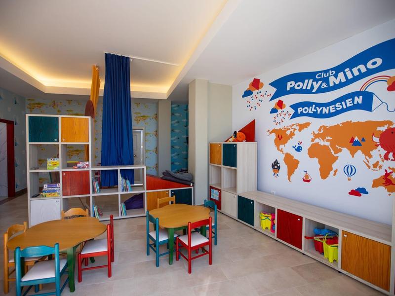 Children's room with colorful tables, chairs, shelves, and Polly Mino themed wall decoration.