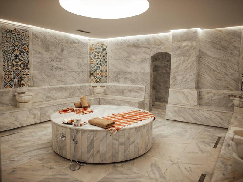 Luxurious marble steam room with rounded seating and decorative wall tiles.