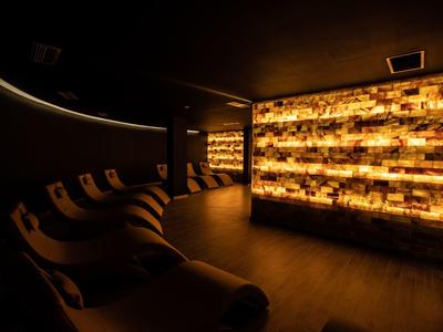 Dark wellness room with illuminated wall and relaxing lounge chairs.