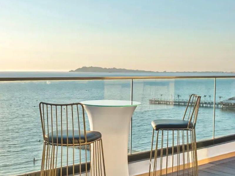 Terrace with two bar stools and a tall table overlooking the sea under clear sky