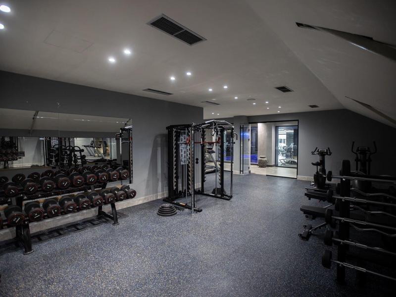 Modern gym with dumbbells, power station, and subdued lighting.