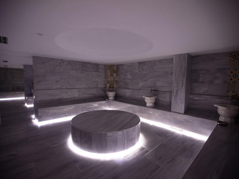 Modern spa area with illuminated round central table and stone walls.