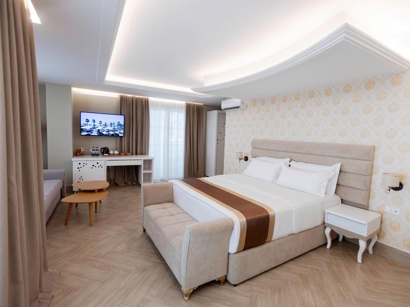 Modern hotel room with double bed, desk, and neutral tones.