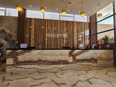 Moderne Hotelrezeption mit marmoriertem Empfangstresen und hängenden goldenen Lampen.