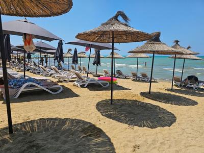Strand mit Liegestühlen und Sonnenschirmen am Meer an einem sonnigen Tag.