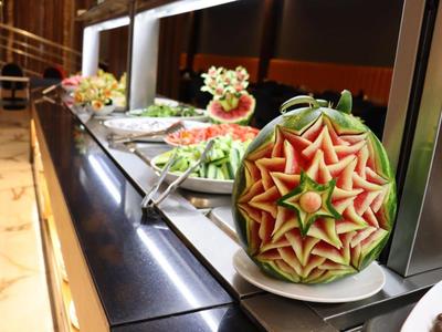 Buffet mit kunstvoll geschnitzten Wassermelonen als Dekoration bei einem Hotelessen.