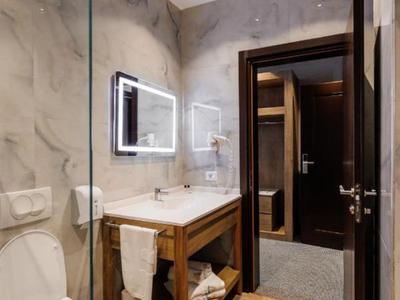 Modernes Hotelbadezimmer mit Holzwaschtisch, beleuchtetem Spiegel und WC.