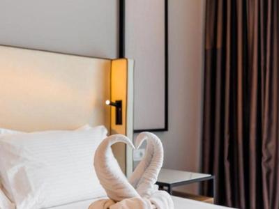 Ein weißes Hotelzimmerbett mit zwei Handtüchern in Form von Schwänen vor dem Kopfteil.