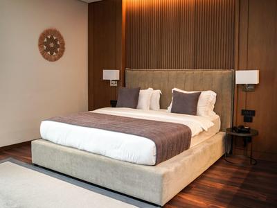 Modernes Schlafzimmer mit großem Bett, Holzboden und dekorativer Wanduhr.