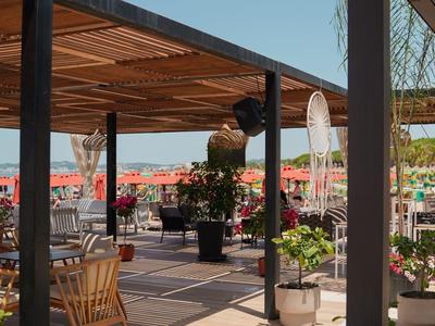 Überdachte Terrasse mit Holzmöbeln und Blumentöpfen unter klarem Himmel.
