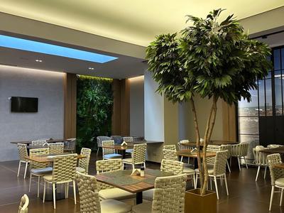 Area lounge moderna dell'hotel con luce naturale brillante e piante.