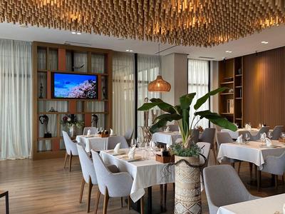 Elegante sala da pranzo dell'hotel con tavoli apparecchiati e illuminazione moderna.