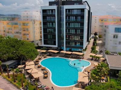 Moderner Hotelkomplex mit Pool in herzförmigem Design und umliegenden Sonnenschirmen