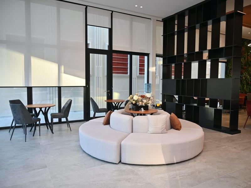 Moderní recepční prostor s kulatou bílou pohovkou a stolky u velkých oken.