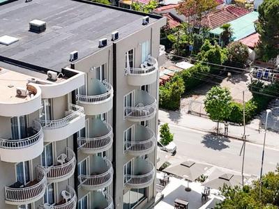 Blick auf ein Hotel mit runden Balkonen und einem Poolbereich, umgeben von Palmen.