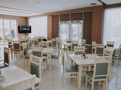 Heller Frühstücksraum mit weißen Tischen und Stühlen mit hellgrünen Polstern.