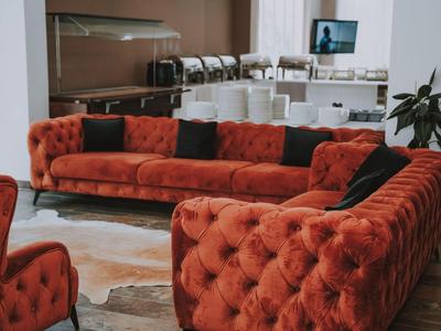 Rotes, samtiges Sofa in L-Form mit schwarzen Kissen in einem modernen Hotelrestaurant.