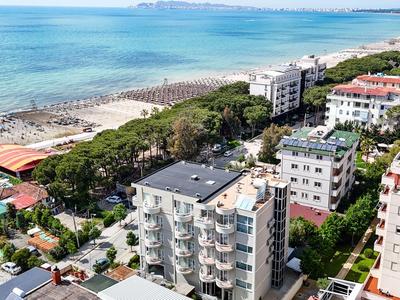 Blick auf Küstenstadt mit Strand, Meer und mehreren mehrstöckigen Wohngebäuden unter klarem Himmel.