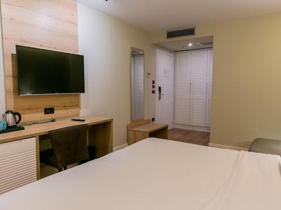 Moderner Hotelzimmerbereich mit Bett, Wandfernseher und Schreibtisch.