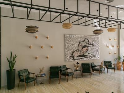 Moderne Hotellounge mit Sitzgruppen, Wandkunst und hängenden Lampen in warmem Licht.