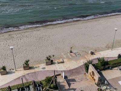 Blick auf einen ruhigen Sandstrand mit Promenade und mehreren Laternen am Meer