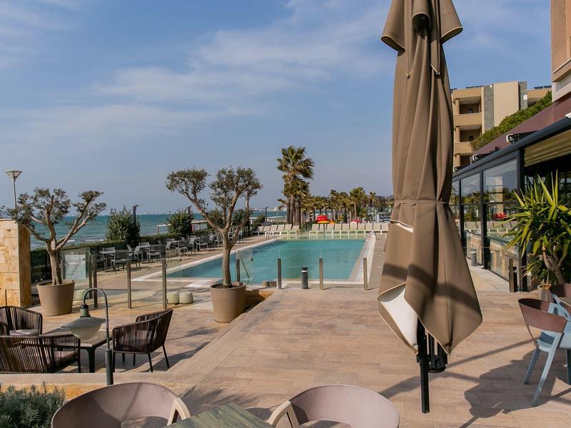 Terrace with seating area and pool, overlooking the sea under clear sky.