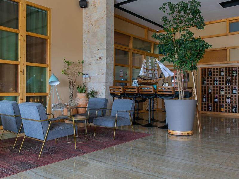 Modern hotel lobby area with seating arrangements and a large potted plant near the reception.