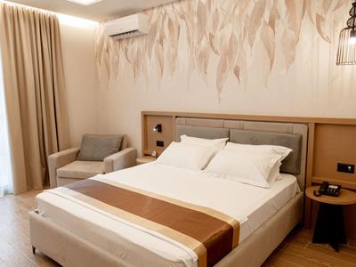 Gemütliches Hotelzimmer mit Doppelbett, Sessel, Nachttischen und einer dekorativen Wandgestaltung.