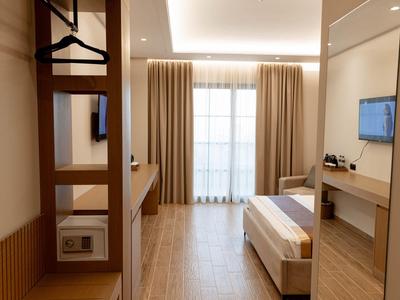 Modern eingerichtetes Hotelzimmer mit Bett, Schreibtisch, Safe und Balkon mit Vorhängen