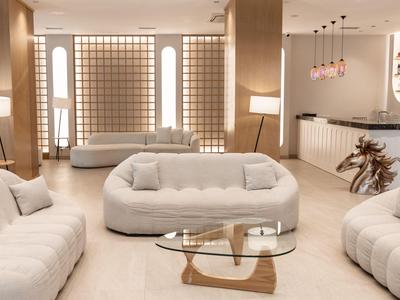 Modern eingerichtetes Wohnzimmer in warmen Tönen mit bequemen Sofas und Glas-Couchtisch.