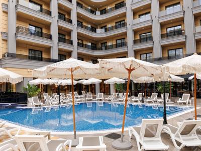 Innenhof eines Hotels mit Pool, Sonnenschirmen und Liegestühlen vor den Balkonen der Zimmer.