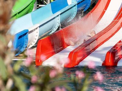 Rutschen in Rot, Blau und Weiß führen in einen Pool mit Wassernebel.