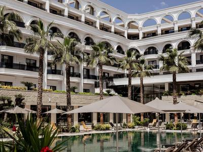 Moderner Hotelkomplex mit Pool, Sonnenschirmen und Palmen in einem sonnigen Klima