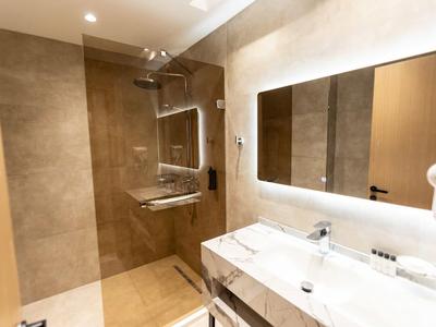 Modernes Badezimmer mit Walk-in-Dusche, großem beleuchtetem Spiegel und Doppelwaschbecken.