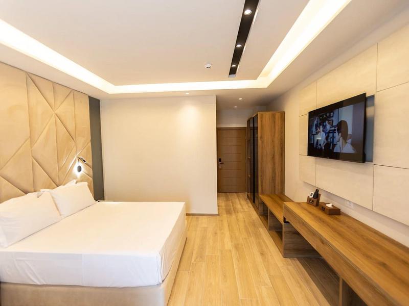 Modernes Hotelzimmer mit großem Bett, Holzboden und Wand-TV.