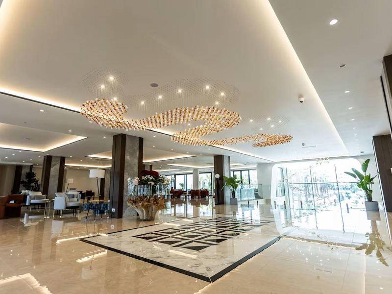 Helle Hotellobby mit modernem Kronleuchter, Marmorboden und großen Fenstern